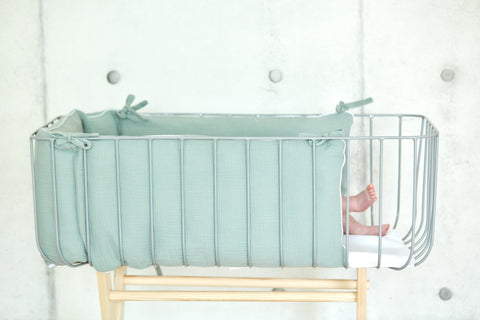 Bettumrandung aus Musselin in Mint im Babybett.