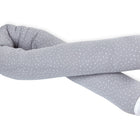 Die KraftKids GmbH Wickeltischrolle Musselin grau Punkte ist ein langes, biegsames graues Körperkissen mit kleinen weißen Punkten und weißen Enden, das auf weißem Hintergrund gewickelt und gekreuzt dargestellt ist.