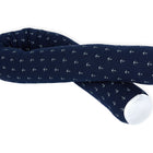 Die KraftKids GmbH Wickeltischrolle Musselin dunkelblau Anker ist ein langes, zylindrisches Kissen in marineblau mit kleinen weißen Ankern und weißen Enden, das locker geschwungen auf weißem Grund abgebildet ist.
