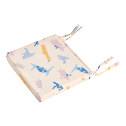 Das KraftKids Sitzkissen für Stühle aus Musselin hat eine quadratische Form, einen pastellfarbenen Dinosaurier-Aufdruck in Blau, Rosa und Gelb, zwei Paar Bänder an gegenüberliegenden Ecken, einen abnehmbaren Bezug und ist auf weißem Hintergrund abgebildet.