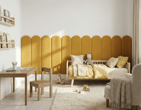 Ein gemütliches Kinderzimmer mit Holzbett, gelber Bettwäsche, Teddybär, flauschigem Teppich, Holztisch und -stuhl, Bücherregalen, verstreutem Spielzeug und Bauklötzen, dazu ein einzigartiges KraftKids Wandpaneel abgerundetes Doppelkrepp im Rundbogen-Design.