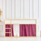 Ein Holzbodenbett mit einer kleinen Leiter und dem KraftKids Hochbettvorhänge Set 2+1 Leinen magenta dunkel für Kura Bett steht vor einer weiß getäfelten Wand. In der Nähe stehen Pampasgras in einer geflochtenen Vase und zwei Holzhocker.