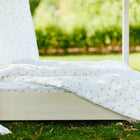 Ein kuscheliges Bett im Freien auf grünem Rasen ist mit dem KraftKids Bettwäscheset Musselin gelbe Zitronen aus 100% Baumwolle mit weißem Stoff und gelben Zitronenmustern gekleidet - perfekt für erholsamen Schlaf unter dem Baldachin.