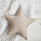 Das KraftKids Sternkissen Musselin beige in Form eines Sterns ruht auf einer weißen Strickdecke auf einer weißen Holzoberfläche - ein idealer Akzent, der jedem Kinderzimmer Charme verleiht.