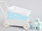 Ein weißer Spielzeugwagen mit dem KraftKids Körbchen weiße Pfeile auf Blau, einem handgenähten blauen Baumwollkorb mit weißen Pfeilen, steht neben pastellblauen und weißen Dekoblöcken auf hellgrauem Hintergrund. Ideal für die Aufbewahrung auf dem Wickeltisch.