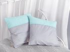 Zwei KraftKids Kissenbezüge "weiße Punkte auf Grau & Mint" liegen auf einer grauen Strickdecke und einem weißen Metallbett mit weißen Vorhängen - eine stilvolle Ergänzung für jede Bettwäschekollektion.