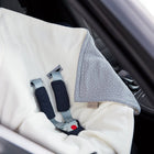 Nahaufnahme eines Autositzes, über den die KraftKids Decke für Babyschale Winter Musselin grau Punkte drapiert ist, mit sichtbaren Sicherheitsgurten und dem Drei-Punkte-Gurt-System im Innenraum eines Autos.