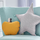 Ein hellblauer Stuhl mit einem gelben Plüsch-Apfelkissen und dem KraftKids Sternkissen Musselin grau Pusteblumen mit kleinen weißen Pusteblumenmustern steht in einem hellen Kinderzimmer neben einer weißen Kommode.