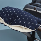 Der KraftKids Kinderwagenmuff Musselin dunkelblau Anker ist ein warmer marineblauer Kinderwagenmuff mit weißen Ankern und weichem Fleecefutter, der am Griff neben einem grauen Stoffkinderwagensitz befestigt wird.