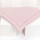 Ein hellrosa, dreieckiges Steppkissen von KraftKids, genannt Wickelauflage Musselin goldene Punkte auf Rosa, mit kleinen goldenen Punkten, ruht auf zwei weißen Würfeln vor weißem Hintergrund.