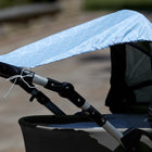 Eine Nahaufnahme eines Kinderwagens mit dem KraftKids Sonnensegel weiße Halbkreise auf Pastellblau. Der Sonnenschirm aus Baumwolle schützt Ihr Kind im Freien, während ein sanft verschwommener Hintergrund sein stilvolles weißes Halbkreismuster hervorhebt.