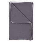 Eine gefaltete KraftKids Babydecke Musselin in Dunkelgrau mit goldenen Punkten und weißem Rand ist auf einem weißen Hintergrund abgebildet.