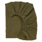 Ein KraftKids Spannbettlaken Doppelkrepp in Herbstgrün, mit elastischen Ecken und strukturierter Oberfläche, ist teilweise gefaltet auf weißem Hintergrund zu sehen.