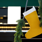 Eine KraftKids Weihnachtssocke Doppelkrepp Gelb Senf hängt an einer mit grüner Tannengirlande geschmückten Leiter, während im Hintergrund ein Klavier und Notenblätter leise verschwimmen.