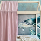 Auf einem Holzhaus-Bettgestell ist die KraftKids Bettbaldachin Doppelkrepp Rosa an einer Seite drapiert und auf der Matratze liegt eine beige Decke. Dahinter sorgt ein Wandbild mit blauen und grünen Walen für das perfekte Kinderzimmer-Deko-Flair.