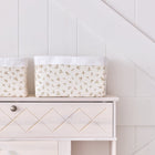 Zwei KraftKids Körbchen Musselin Zweige braun aus Baumwolle stehen zur Aufbewahrung auf einer hellen Holzkommode vor weißer Paneelwand, rechts ist ein schwarzer Griff zu sehen.