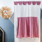 Eine verspielte Zimmerszene mit dem KraftKids Puppentheater Kasperletheater Musselin rosa inkl. Teleskopstange. Teleskopstange an der Wand, einem Strohlöwengesicht als Dekoration und einer schwarzen Kreidetafel mit bunten Zeichnungen in der Ecke.