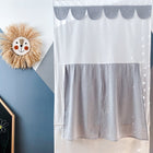 An einer Wand befindet sich ein handgefertigtes Löwengesicht aus Stroh, das KraftKids Puppentheater Kasperletheater Musselin grau Pusteblumen mit grauer Spitze und gemustertem Vorhang, sowie eine Kreideecke mit bunten Zeichnungen auf einer geometrisch bemalten Wand.